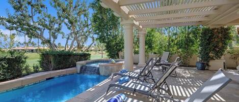 A pool area with lounge chairs and a pergola.