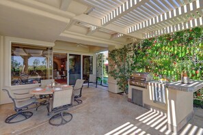 Une terrasse extérieure avec une table à manger, des chaises et un barbecue.
