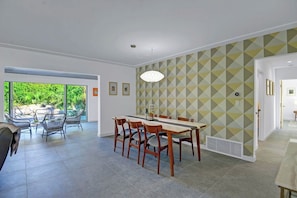 A dining area with a table and chairs, a patterned wall, and a view of greenery outside. - Casa San Lucas - Central Palm Springs (Palm Springs)