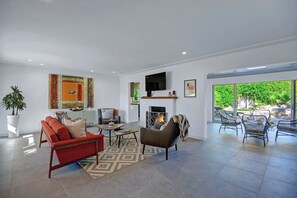 Een moderne woonkamer met een open haard, zithoek en grote ramen.