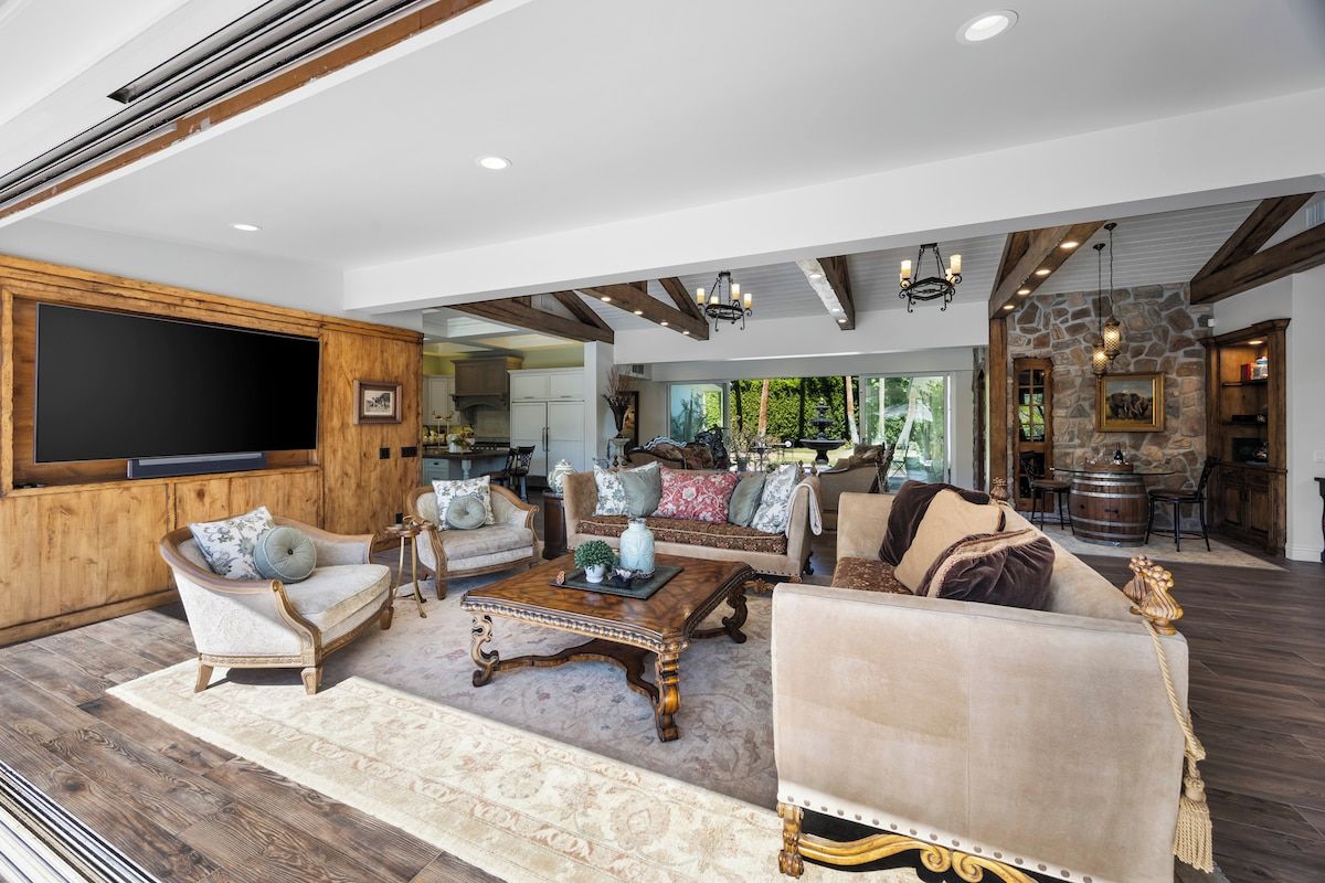 A spacious living area with a large flat-screen TV, multiple sofas, a coffee table, and a stone fireplace.