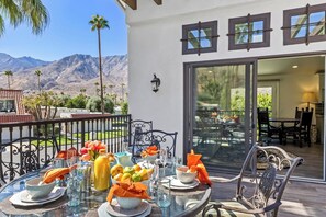 An outdoor dining area with a table set for two, surrounded by chairs, with a mountain view in the background. - Casa Sueños - Andreas Hills (Palm Springs)