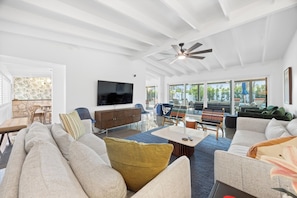 A modern living room with a flat-screen TV, comfortable seating, and a ceiling fan. - Sun & Stone Retreat (Palm Springs)