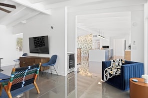 A modern living space with a dining area, a kitchen, and a seating area with a blue sofa. - Sun & Stone Retreat (Palm Springs)