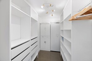 A white closet with shelves, drawers, and hanging space, featuring a ceiling light fixture. - Sun & Stone Retreat (Palm Springs)