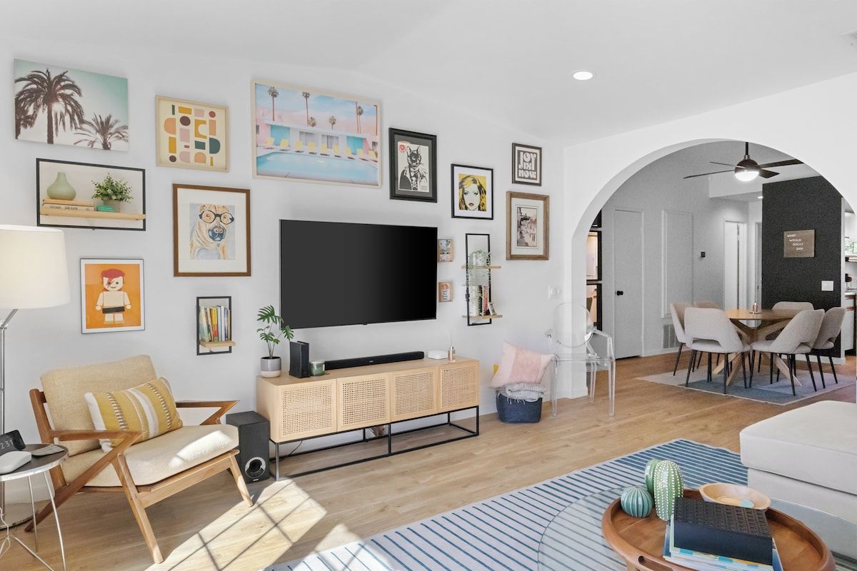 Een moderne woonkamer met een flatscreen televisie, een bank, een salontafel en diverse kunstwerken aan de muur.