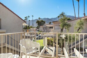 A balcony with white chairs, a staircase, and a view of palm trees and mountains. - Mesquite WorkPlay Oasis - Central PS (Palm Springs)