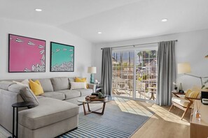A modern living room with a sofa, coffee table, and a view of a courtyard through large glass doors. - Mesquite WorkPlay Oasis - Central PS (Palm Springs)