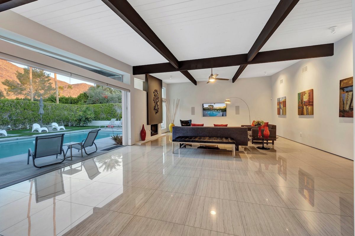 A spacious living area with a pool, modern furniture, and artwork on the walls.