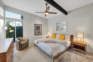 Ein modernes Schlafzimmer mit Bett, Nachttischen, einem Sessel und einem Schreibtisch.