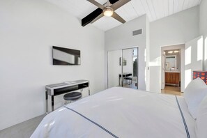 A modern hotel room with a bed, a desk, a chair, a television, and a ceiling fan. - Casa La Vista - MidCentury Home (Palm Springs)