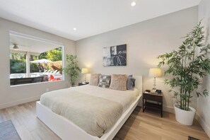 Ein Schlafzimmer mit einem großen Bett, Nachttischen, einem Spiegel und einer Zimmerpflanze.