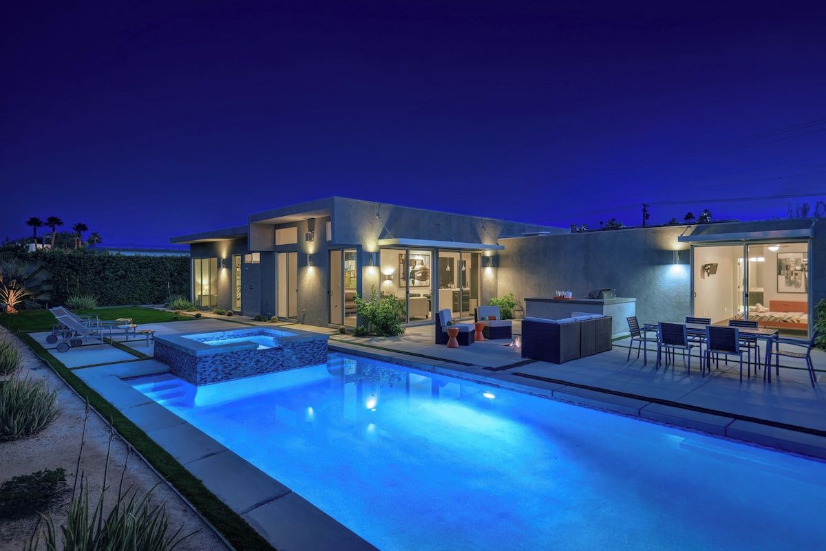 Ein modernes Haus mit Swimmingpool, Sitzgelegenheiten im Freien und einer gut beleuchteten Terrassenfläche.