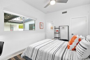 Ein Schlafzimmer mit Bett, Fenster, Tür und Deckenventilator.