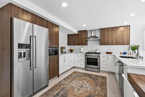 Eine moderne Küche mit Edelstahlgeräten, Holzschränken und einem gemusterten Teppich.