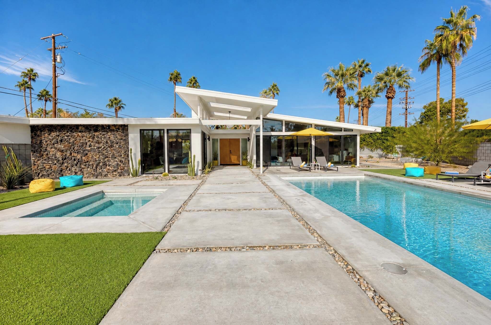 Uma casa moderna com piscina, um pátio e palmeiras.
