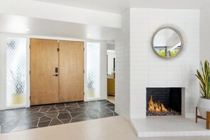 Ein modernes Interieur mit einer Holztür, einem Kamin und einem runden Spiegel an der Wand.