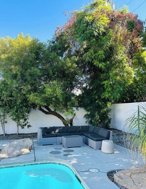 A poolside area with a built-in seating arrangement and a tree providing shade. - Retro Rendezvous - South PS (Palm Springs)