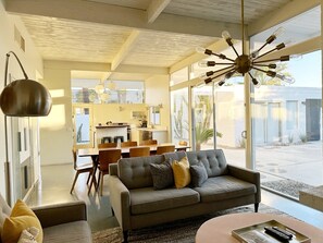A modern living room with a sofa, a dining area, and a kitchen in the background. - Retro Rendezvous - South PS (Palm Springs)