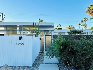 A modern building with a white exterior, a visible door, and a number '1003' on the wall. - Retro Rendezvous - South PS (Palm Springs)