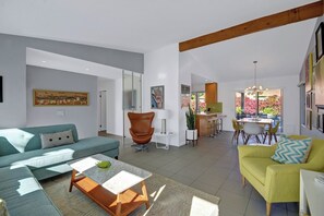 Ein modernes Wohnzimmer mit Sofa, Sesseln, Couchtisch und Essbereich mit Stühlen und Tisch.