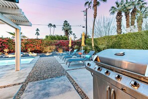Eine Terrasse im Freien mit Grill, Liegestühlen und Schwimmbecken.