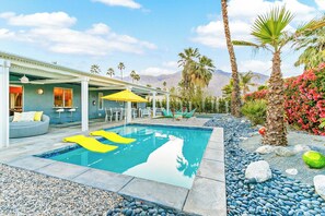 A swimming pool with a clear blue water, surrounded by pebbles and rocks. - Sunrise Paradise: Palm Springs Home with Private Pool and Mountain Views (Palm Springs)