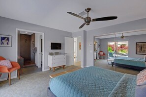 Ein Schlafzimmer mit einem Bett, einem Schminktisch, einem Fernseher und einem Deckenventilator.