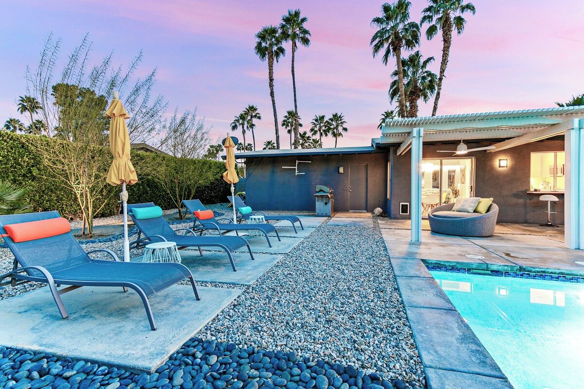 A poolside area with lounge chairs, a small pool, and a building with a modern design.