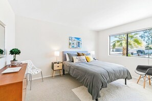 A modern bedroom with a bed, bedside tables, a desk, a chair, and a large window with a view. - Dreamville Palm Springs by Oranj Palm (Palm Springs)