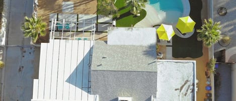 Oversigtsbillede af en ejendom med swimmingpool, overdækket terrasse og en lille bygning med fladt tag.