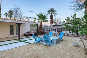 An outdoor patio with blue chairs, a fire pit, and a covered seating area. - Dreamville Palm Springs by Oranj Palm (Palm Springs)