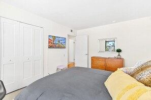 Ein Schlafzimmer mit Bett, Kommode, Stuhl und einem Bild an der Wand.