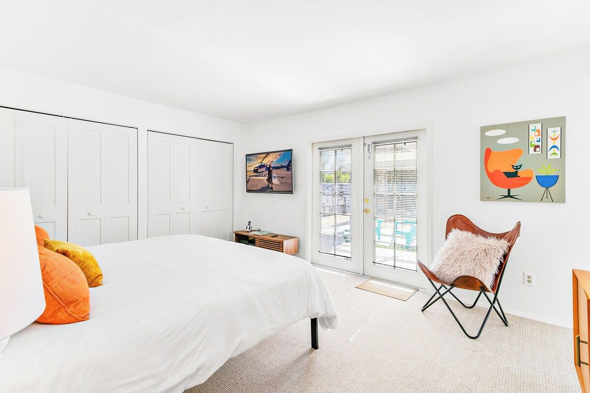 A bedroom with a bed, a chair, a window, and a door.