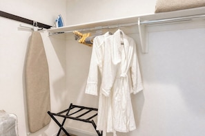 Ein Badezimmer mit Handtuchhalter, einem beigen Handtuch und zwei weißen Bademänteln.
