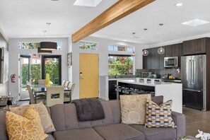 A modern kitchen with a central island, stainless steel appliances, and pendant lighting. - Yellow Palms - Warm Sands (Palm Springs)