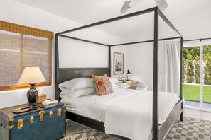 Ein Bett mit Baldachin, ein Nachttisch, eine Lampe und ein dekorativer Koffer.