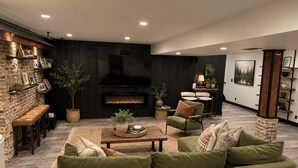 Ein modernes Wohnzimmer mit einem grünen Sofa, einem Kamin und einem Essbereich mit Tisch und Stühlen.