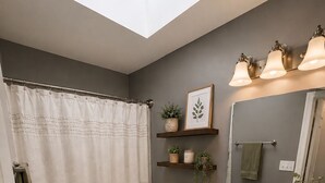 Ein Badezimmer mit Oberlicht, Toilette, Waschbecken und Duschvorhang.