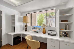 Un espace de bureau moderne avec un bureau incurvé, un écran d’ordinateur, une lampe et une chaise.