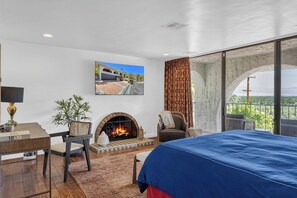 Ein Hotelzimmer mit Kamin, einem Bett, einem Schreibtisch und Blick ins Freie.