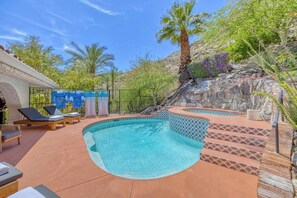 Ein Pool mit gewölbter Kante, umgeben von Liegestühlen und einer Steinmauer.