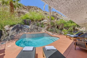Une piscine avec des chaises longues et un paysage rocheux.
