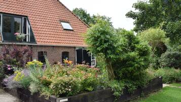 A house with a sloped roof, a brick exterior, and a garden with various plants and flowers.