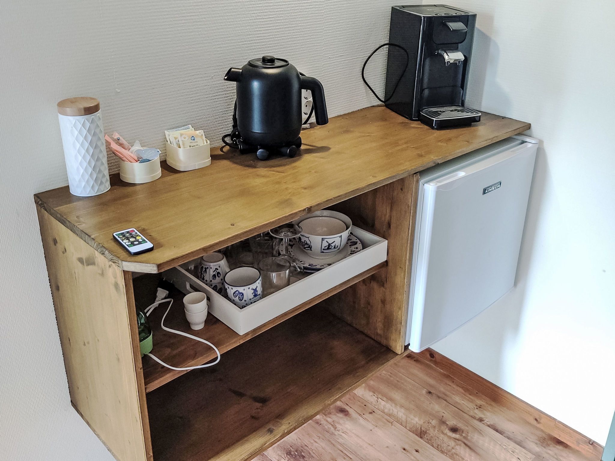 A compact kitchenette with a coffee maker, a kettle, and a small refrigerator.