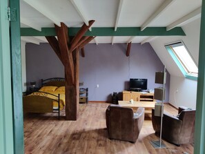 A room with a sloped ceiling, a bed, a television, a desk, and a chair. - Taniaburg Gästezimmer 2 by Interhome (Leeuwarden)
