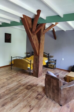 A room with a wooden tree-like structure, a bed with yellow bedding, a brown leather chair, and a wooden floor. - Taniaburg Gästezimmer 2 by Interhome (Leeuwarden)