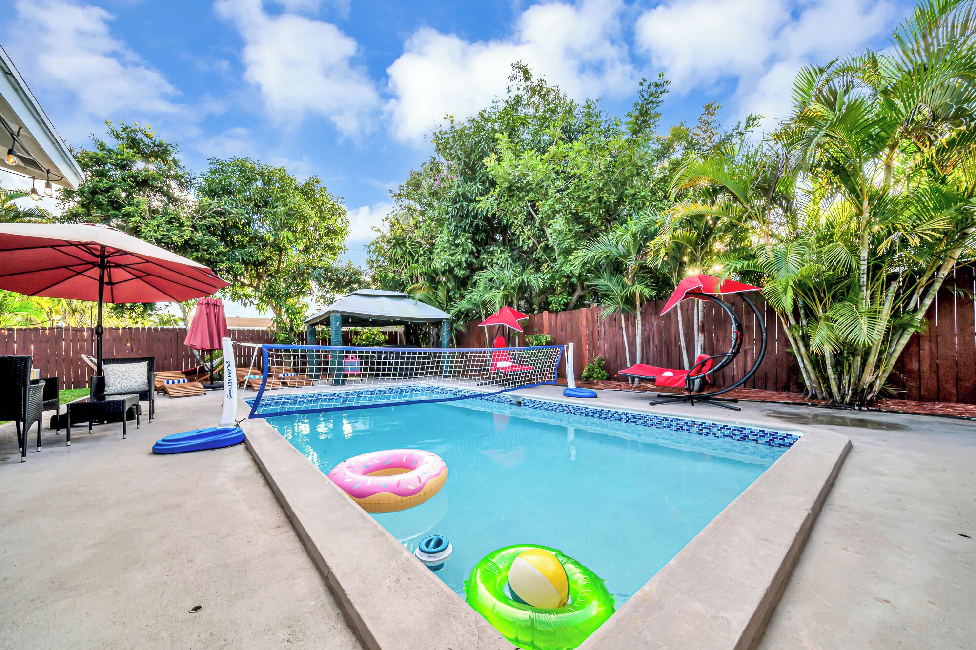 Un patio trasero con piscina, tobogán y mobiliario de exterior.