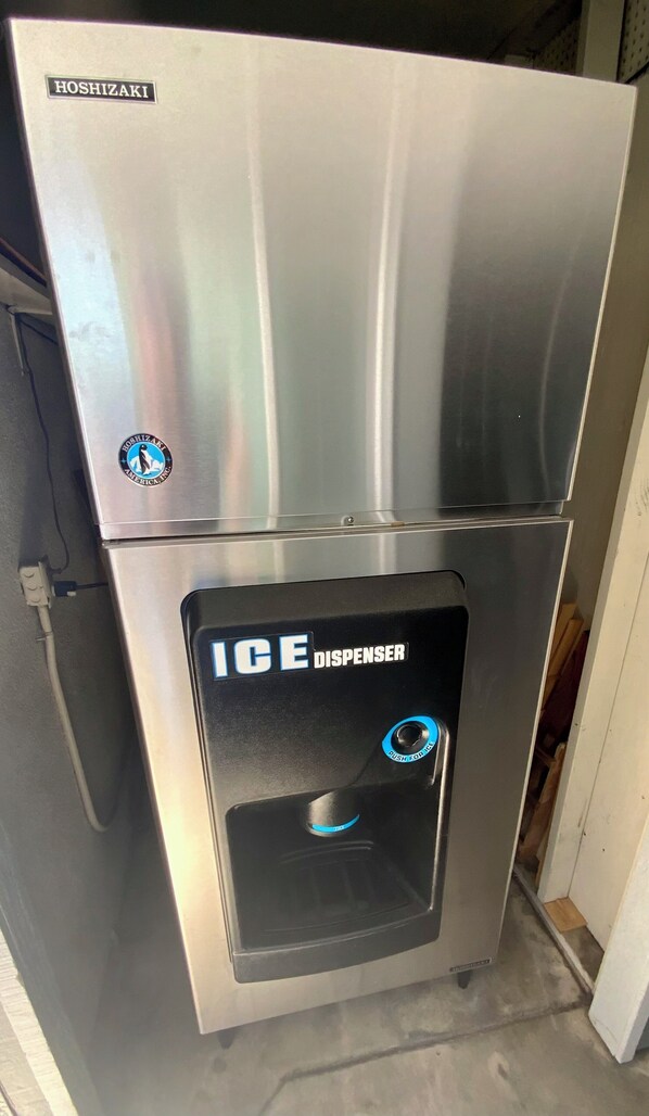 Dispensador de hielo Hoshizaki de acero inoxidable con un botón pulsador y un logotipo en la parte superior.