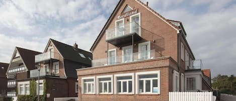 A two-story brick building with a flat roof, a balcony on the upper floor, and a sign that reads 'Nordland.'